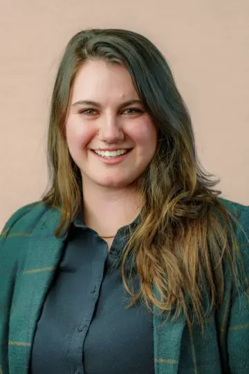 Meredith Tierney-Beed smiling in front of plain tan background