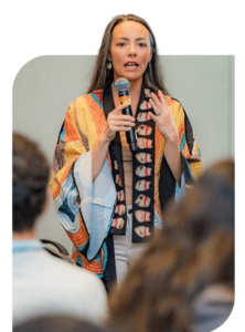 Melissa Horner with microphone speaking to a crowd during Summer Institute.