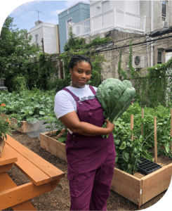 Dr. Ashley B. Gripper holding vegetable in community garden.