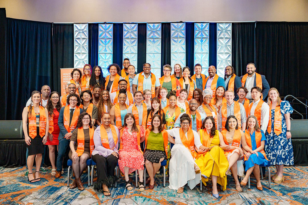 Group of 2024 graduating scholars with orange stoles smiling.