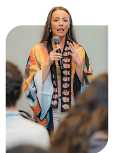 Melissa Horner with microphone speaking to a crowd during Summer Institute.