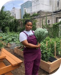 Dr. Ashley B. Gripper holding vegetable in community garden.